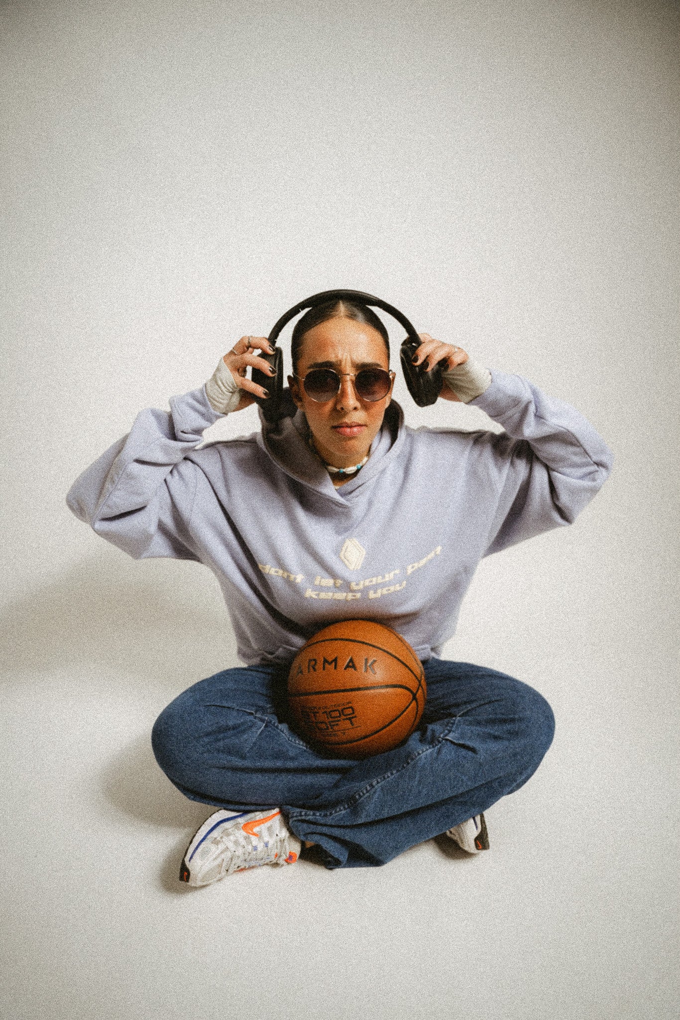 Person mit Sonnenbrille und Kopfhörern, die einen Basketball hält, trägt einen oversized Unisex-Hoodie in Hellblau mit Drop-Shoulder-Passform. Der Hoodie mit doppelten Nähten und aus schwerer French Terry Baumwolle bietet Komfort, Langlebigkeit und Atmungsaktivität. Auf der Brust steht der Schriftzug 'don't let your past keep you'. Der zweite Teil der Botschaft, 'from your best', ist nicht sichtbar. Das Logo der Marke 'BAKLAVA' ist ebenfalls zu erkennen. Inspiriert von Kendrick Lamar’s Song 'Die Hard'.